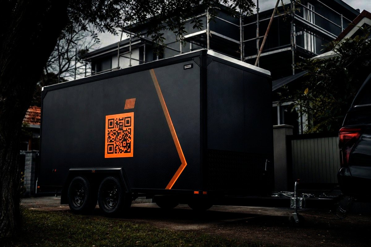 Box trailer on a job site driveway with a QR sticker on the side